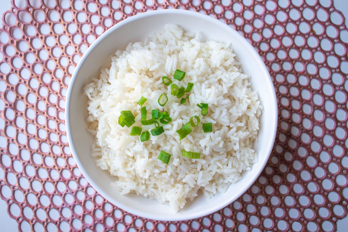 A bowl of fluffy white rice topped with chopped green herbs