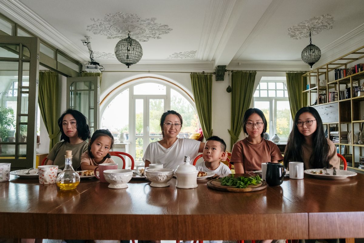 A family of six seated around a dining table with bowls of food