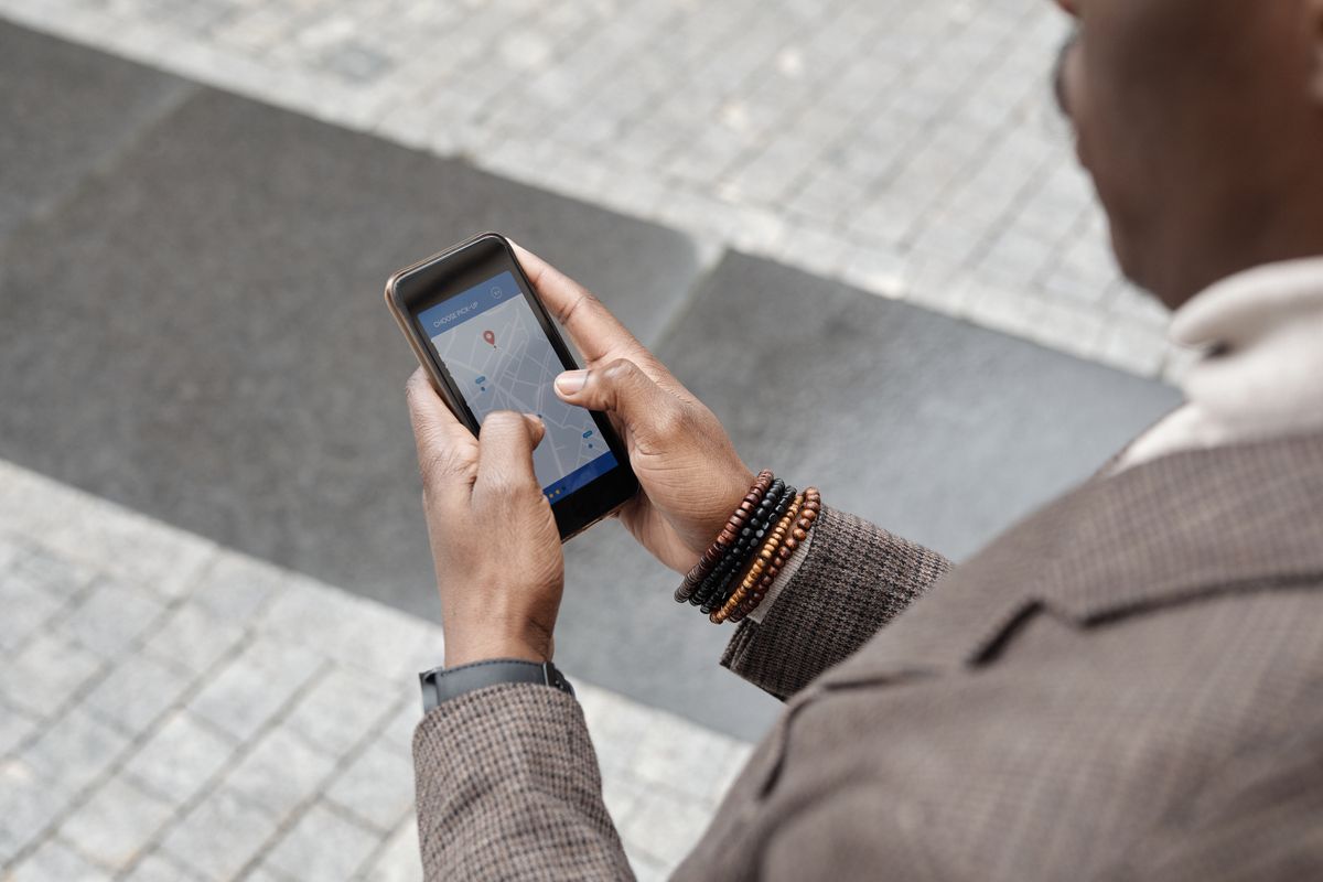 A person on a city street using a map app on a phone with a location pin showing