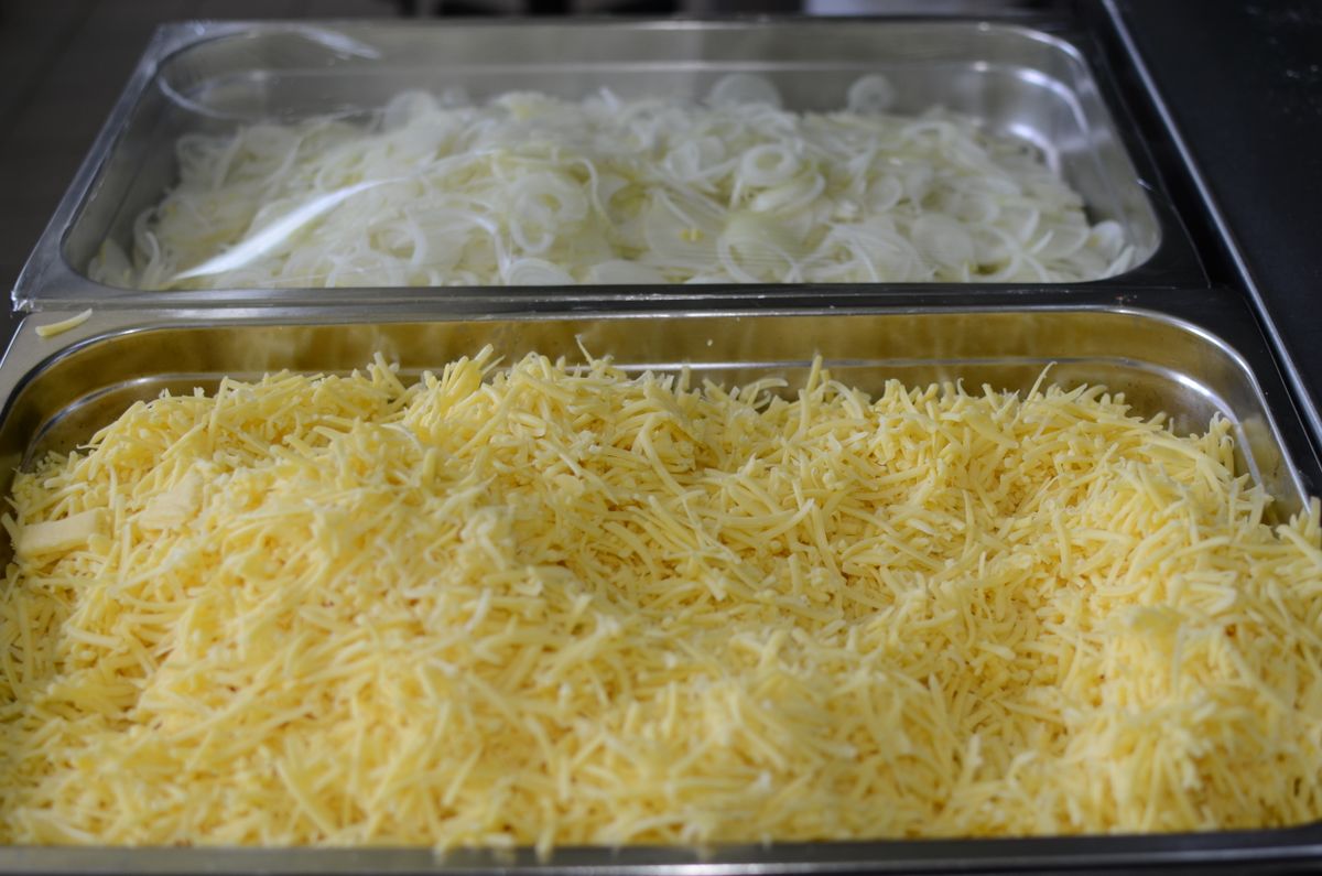 Shredded cheese and sliced onions in prep trays