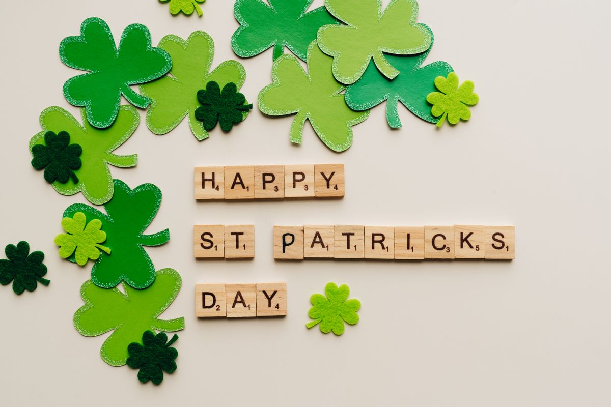 Paper shamrocks beside letter tiles spelling HAPPY ST PATRICKS DAY