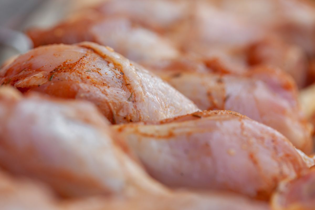 Raw chicken pieces coated in a dry red seasoning