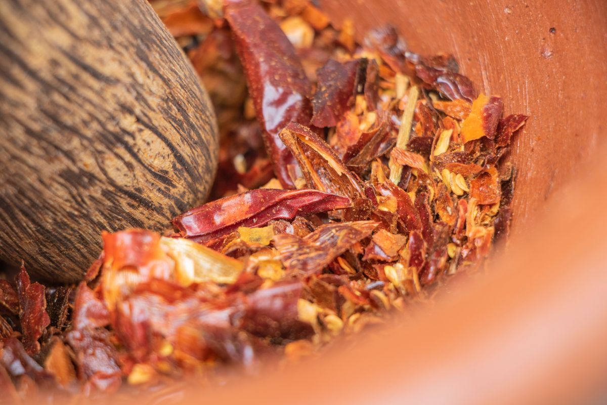 Red chilli peppers being ground down in a stone mortar